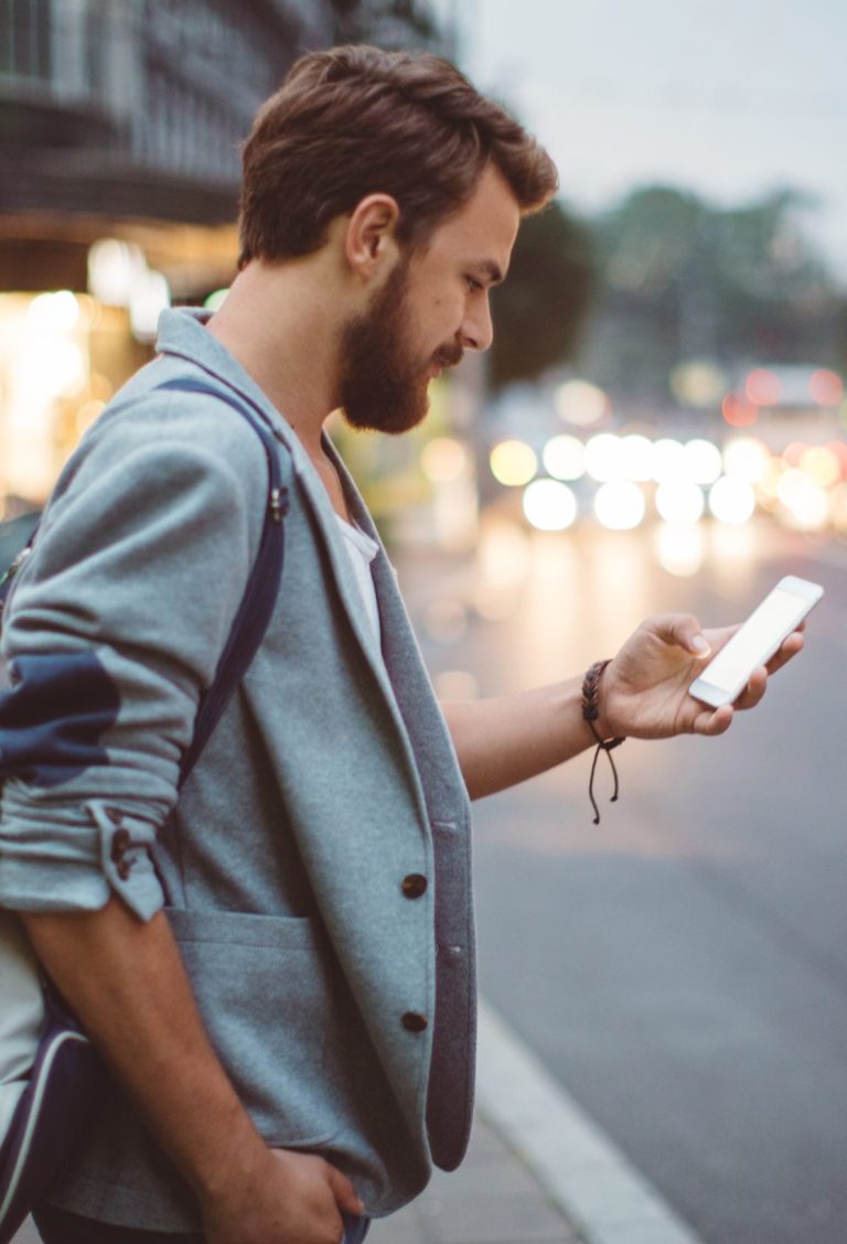 Young man on the streets of big city. TicketPlus+ Phone Screen in Hand